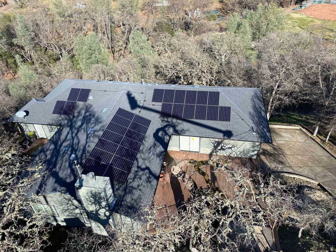 An aerial view of a house with solar panels on the roof.