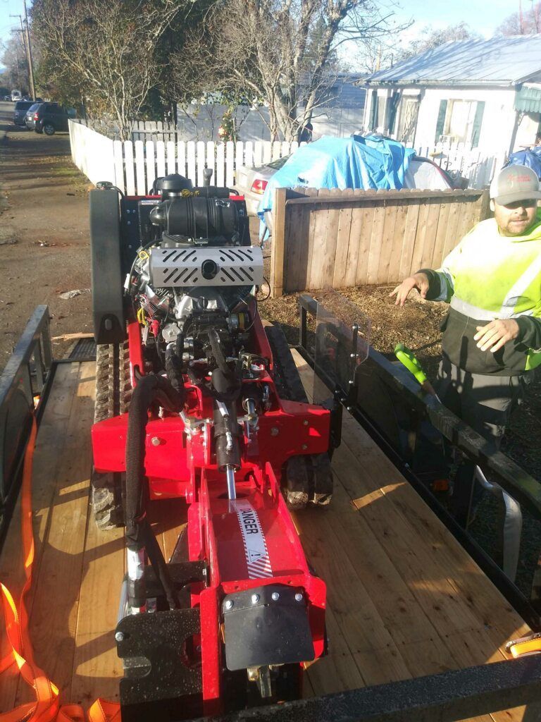 A man is standing next to a red machine on a trailer.