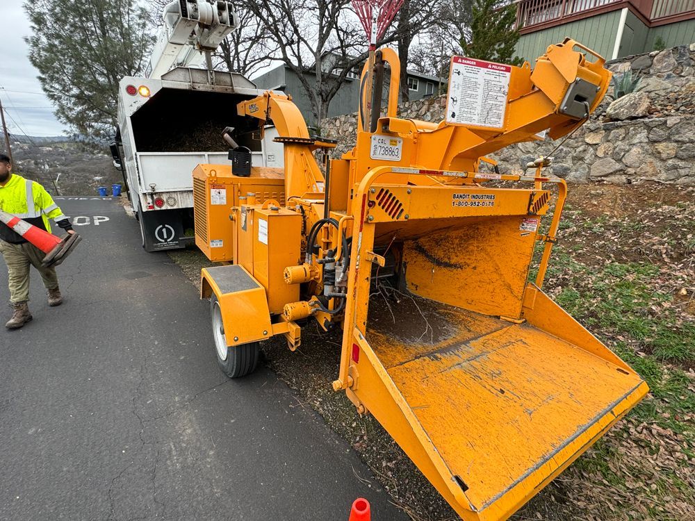 A man is standing next to a large yellow machine on the side of the road.