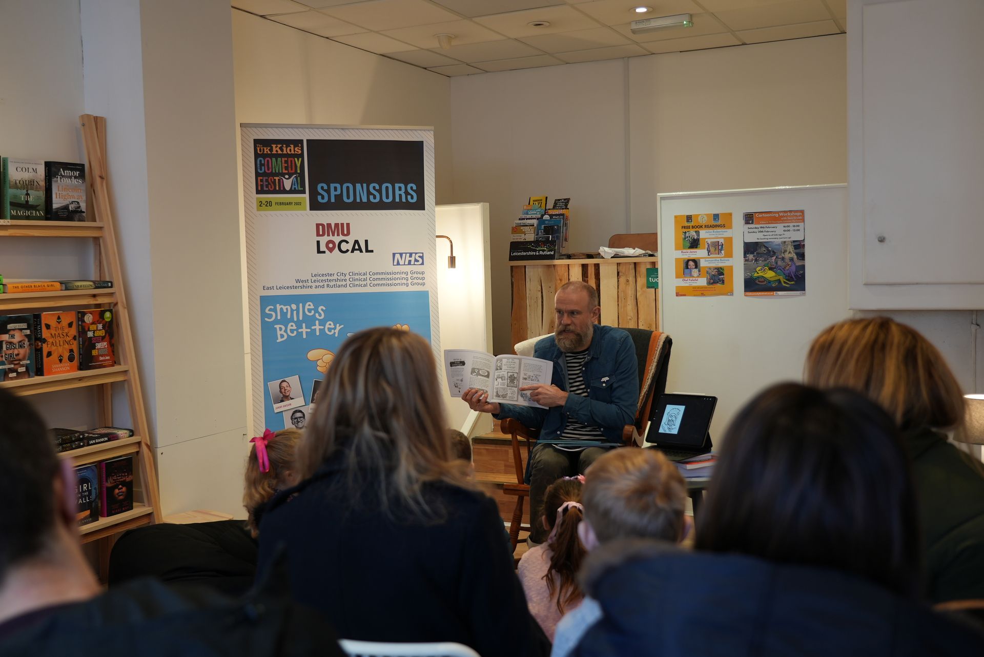 Two people on a stage with a presentation screen and banner. The setting is a theater.