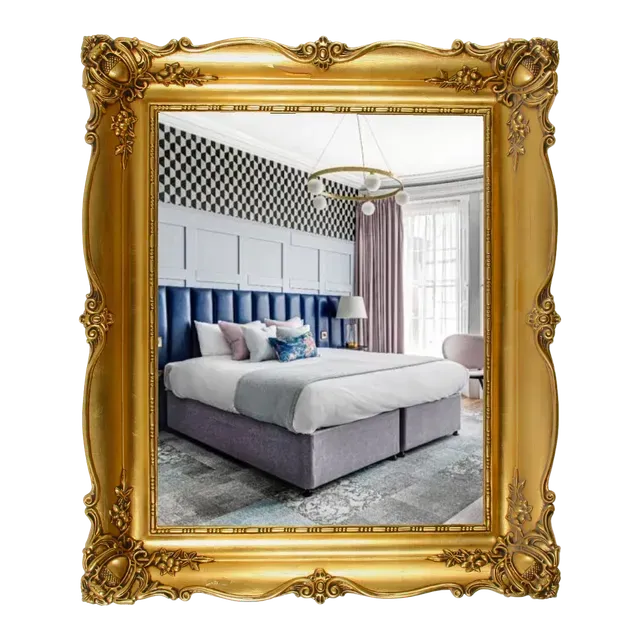 Gold ornate frame displaying a hotel bedroom: bed, patterned wallpaper, window with curtains.