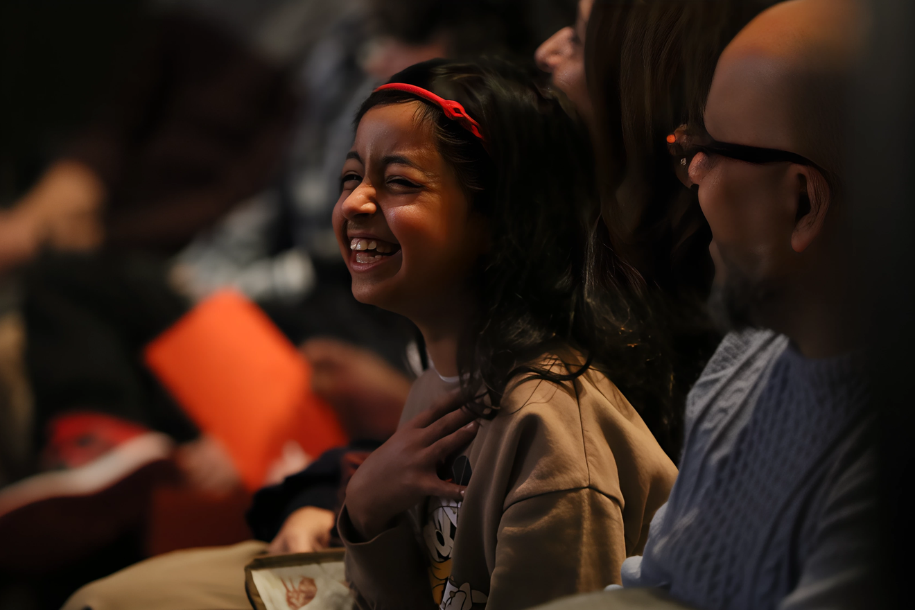 Man in blue suit, smiling, looking upwards against a teal background.