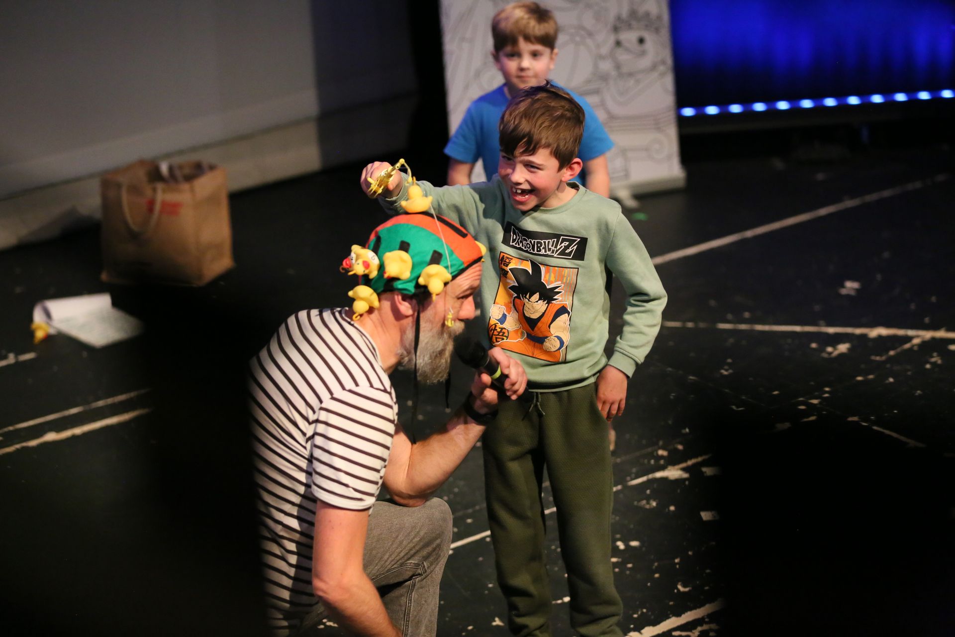 Man with long brown hair, black shirt, crossed arms, looking surprised, light blue background.