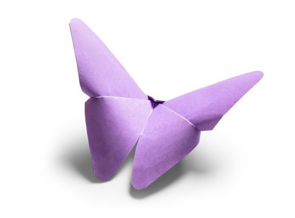 A purple origami butterfly is sitting on a white surface