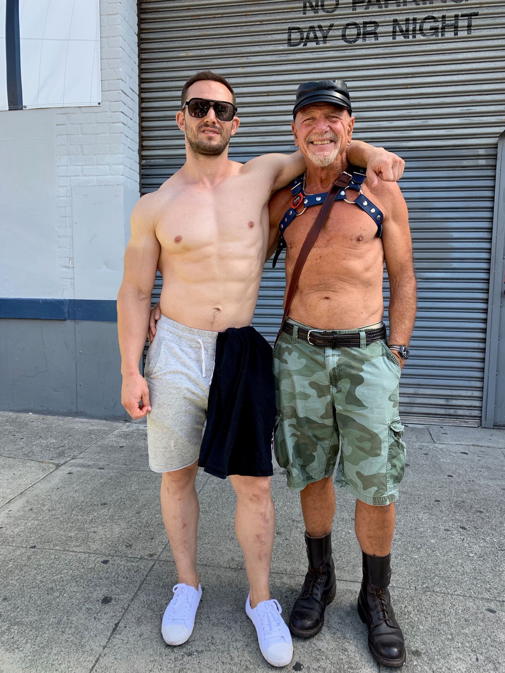 Two men are posing for a picture in front of a building that says day or night