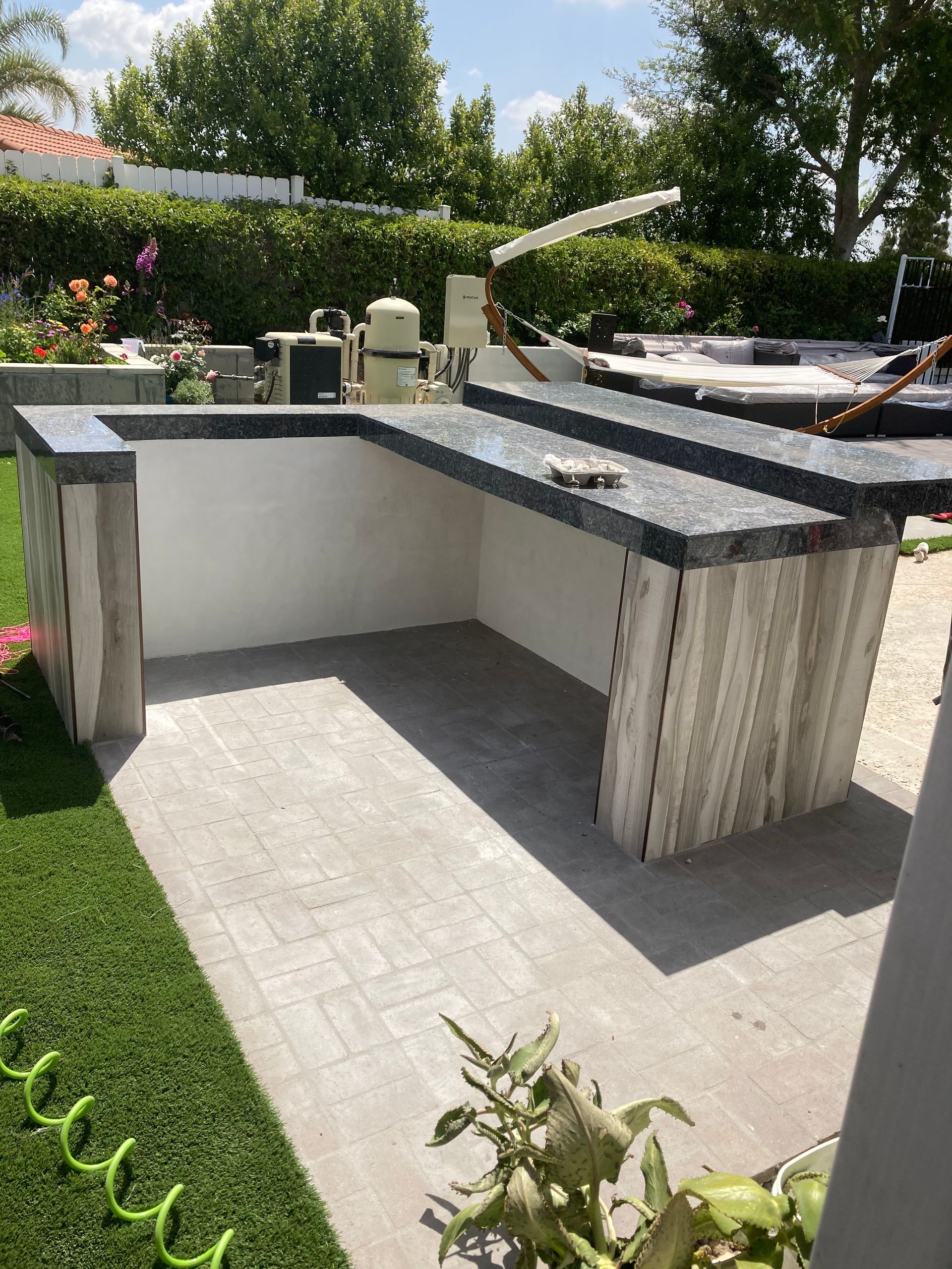 A large outdoor kitchen is being built in a backyard.