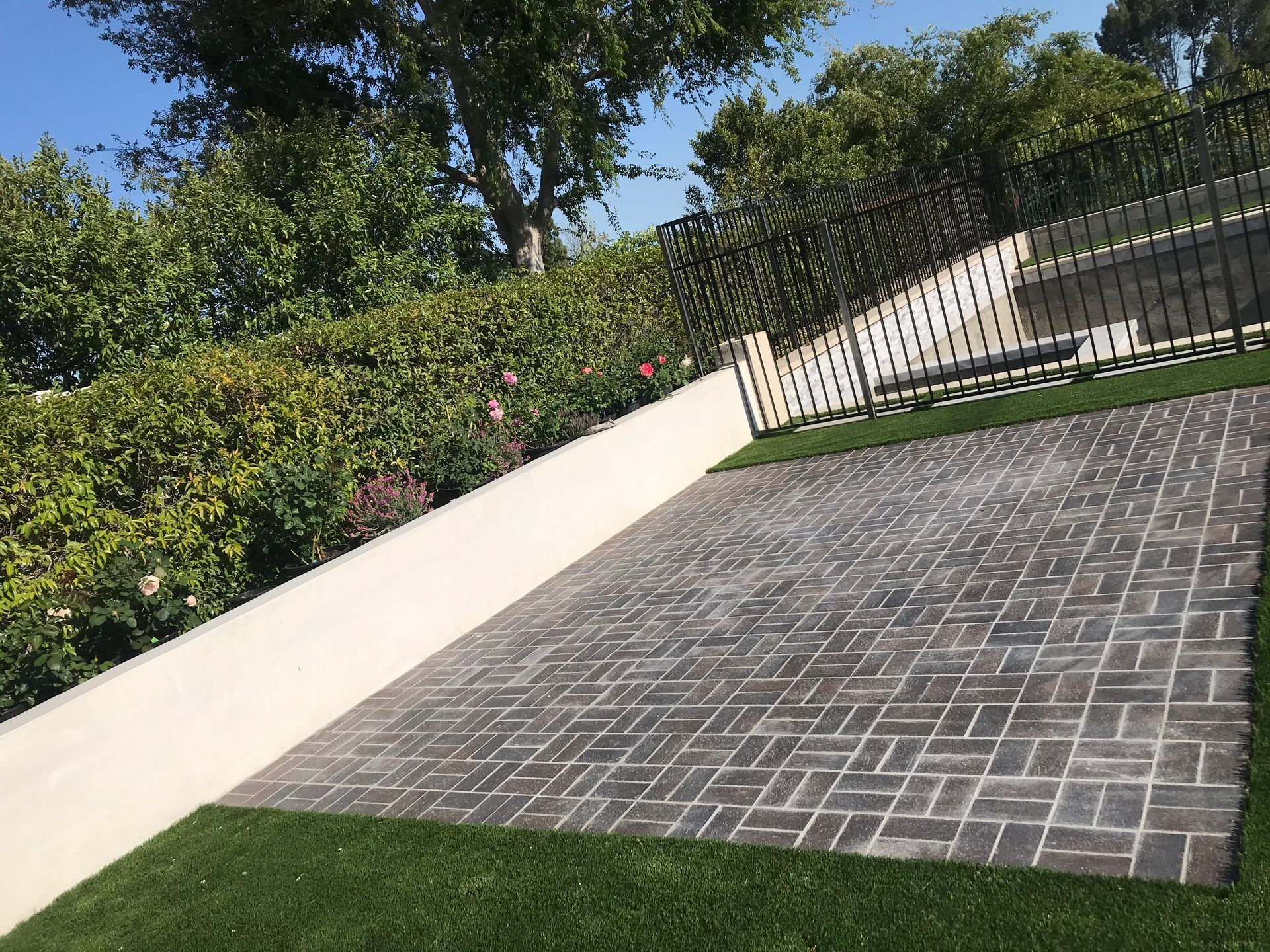 A brick driveway with a fence and trees in the background