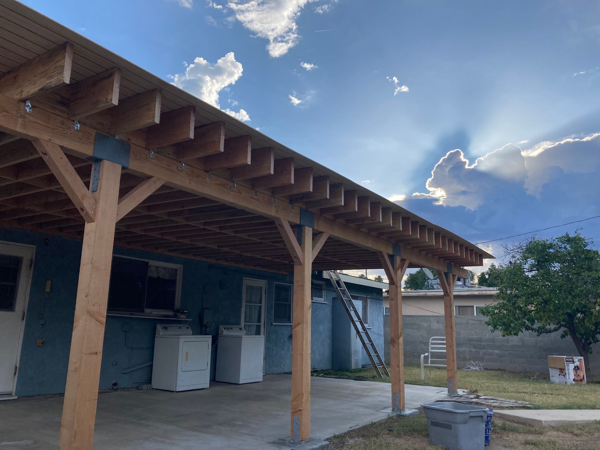 A wooden covered patio with a washer and dryer underneath it.