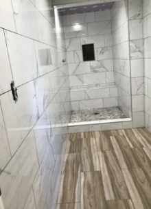 A bathroom with white tiles and wooden floors and a walk in shower.