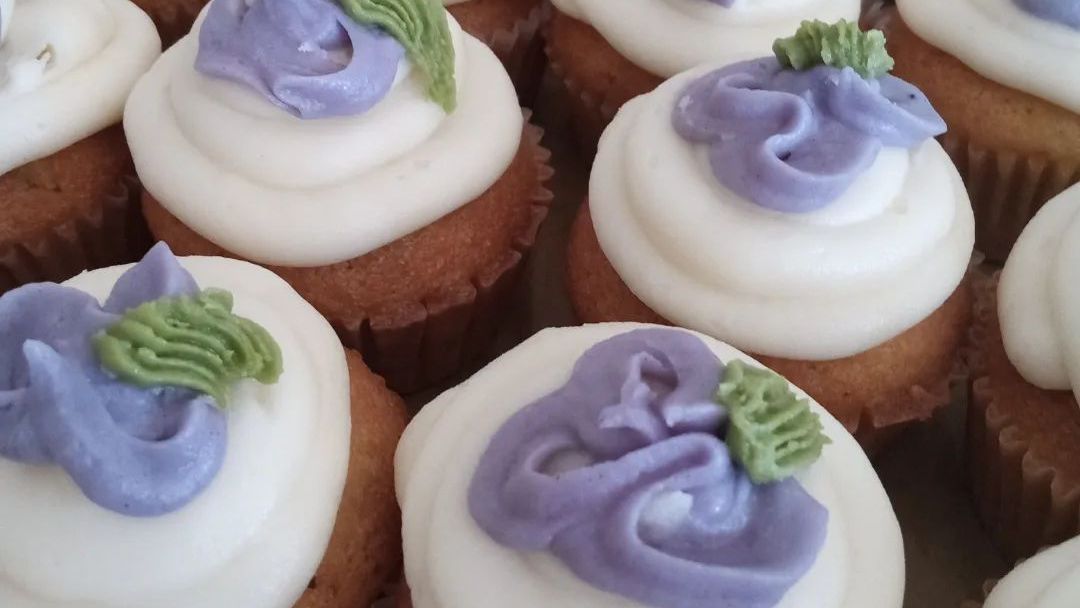 A bunch of cupcakes with white frosting and purple frosting