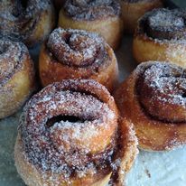 A bunch of cinnamon rolls covered in powdered sugar on a table.