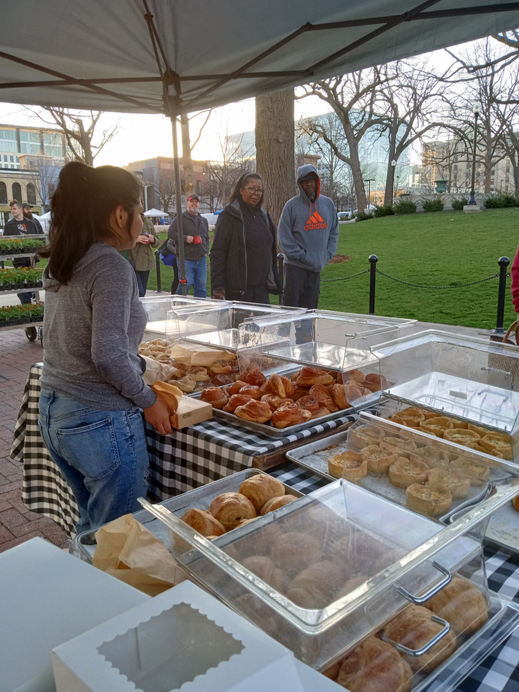 A woman is standing in front of a table full of food.