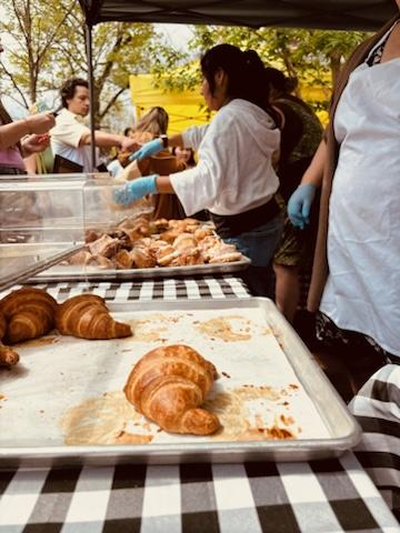 A woman is standing in front of a display of croissants.