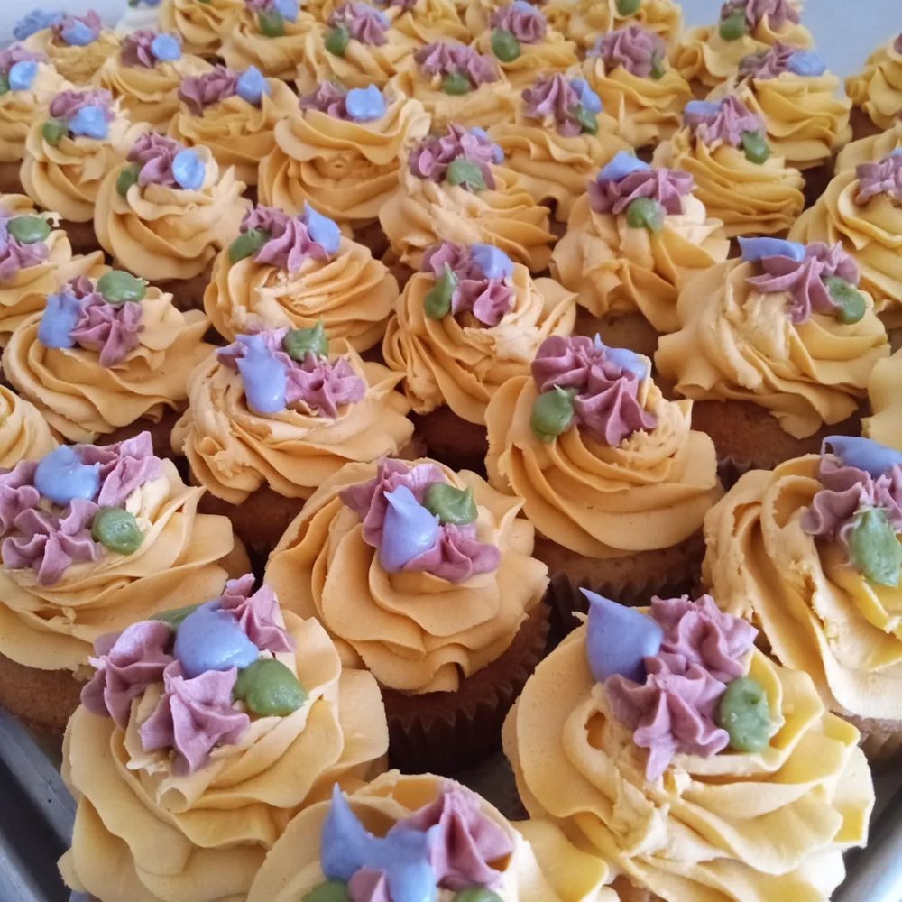 A bunch of cupcakes with yellow frosting and purple frosting