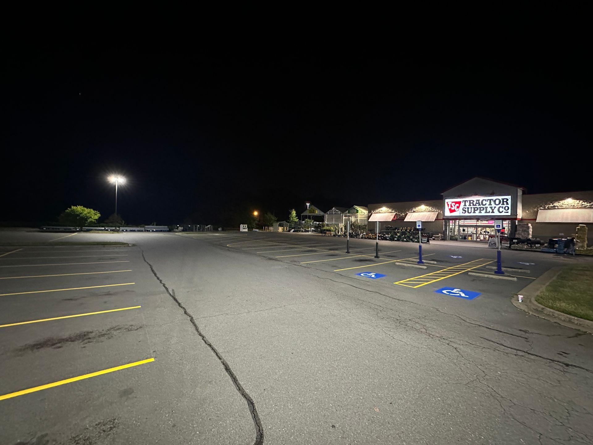 Empty parking lot at night with a partially lit store in the background.
