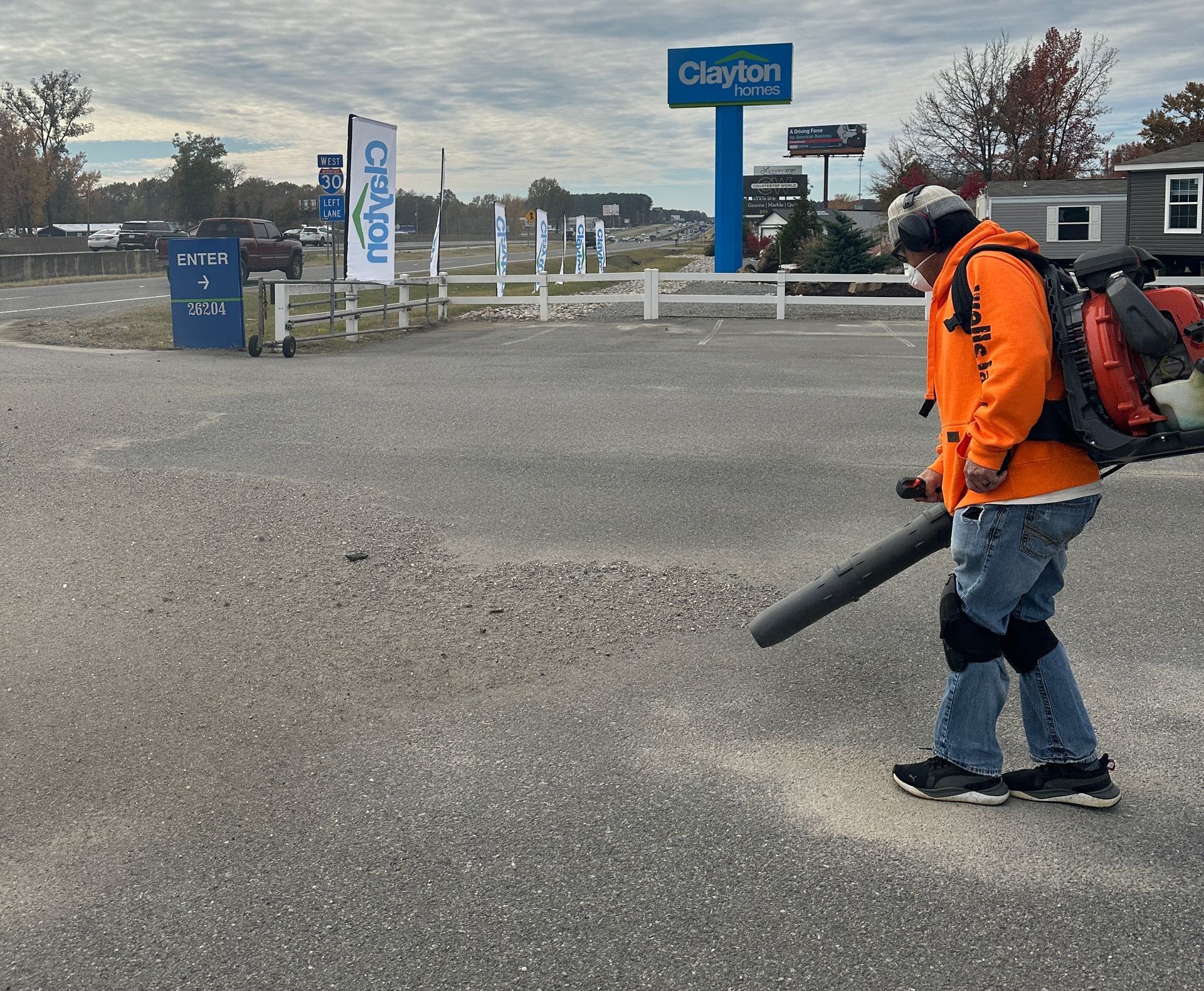 A man is blowing a parking lot clean free from debris and dirt