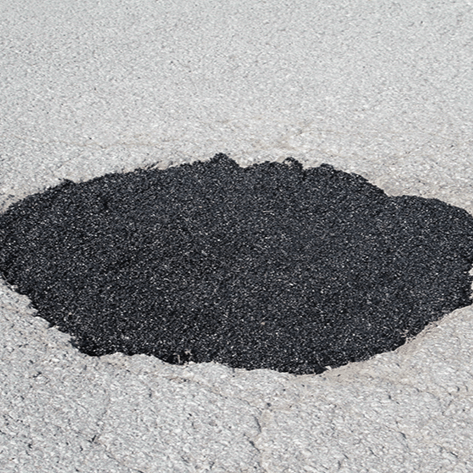 Black line painting machine applying a fresh stripe on a paved surface. Sunny outdoor setting.