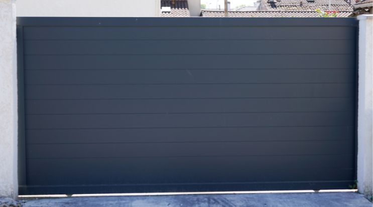 Dark gray horizontal sliding gate between two white pillars.