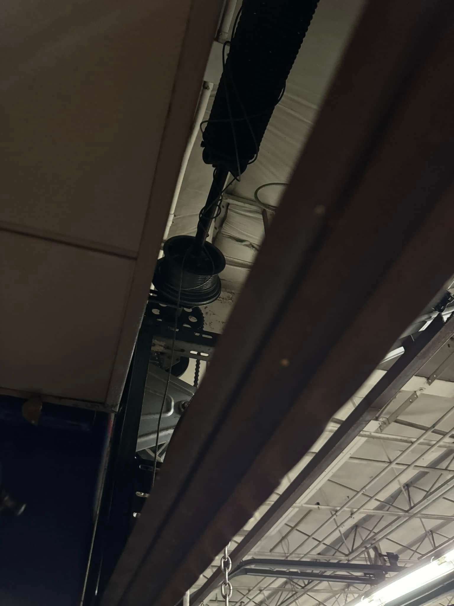 Overhead view of theater lighting fixtures mounted on a metal beam, black ceiling visible above.