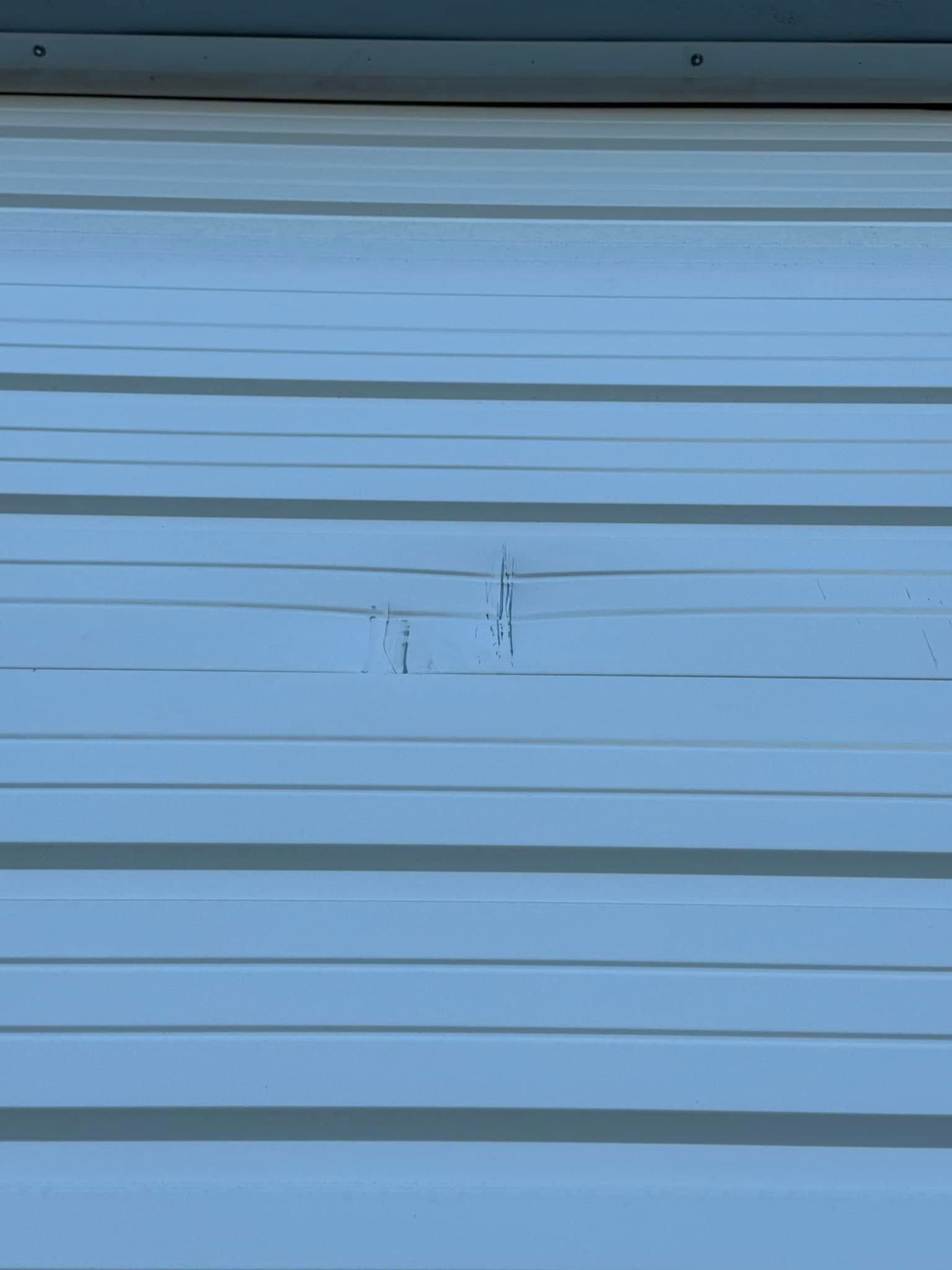 White corrugated metal siding with a small dent and some scratches.