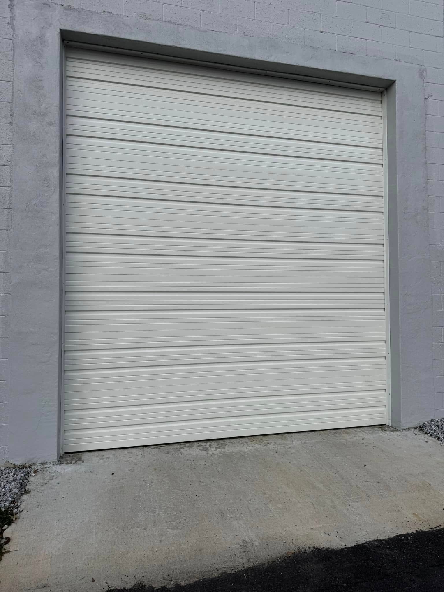 Gray roll-up door in a concrete frame, set in a slanted concrete base.