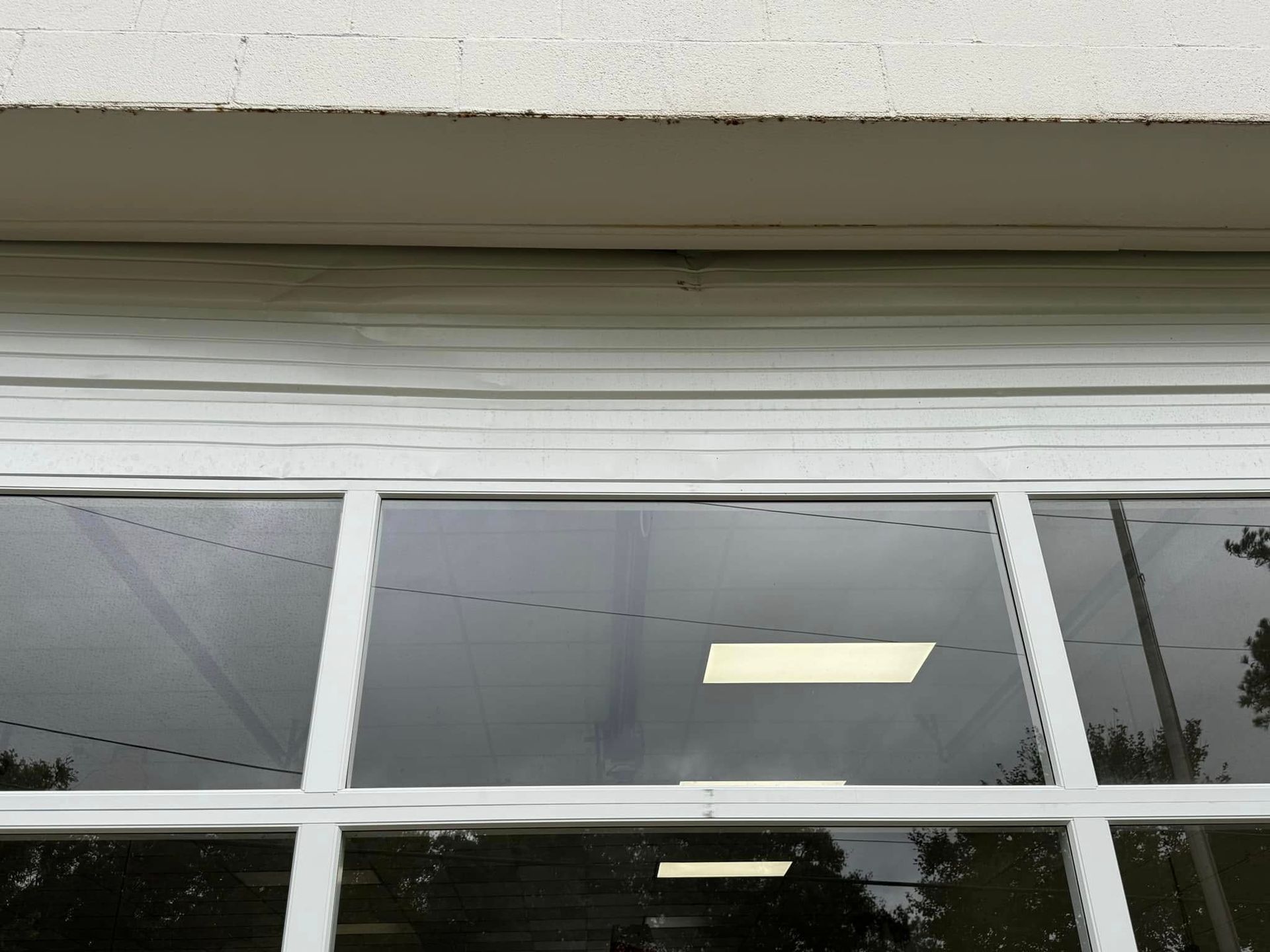 White paneled window with reflected sky and a bright light indoors.