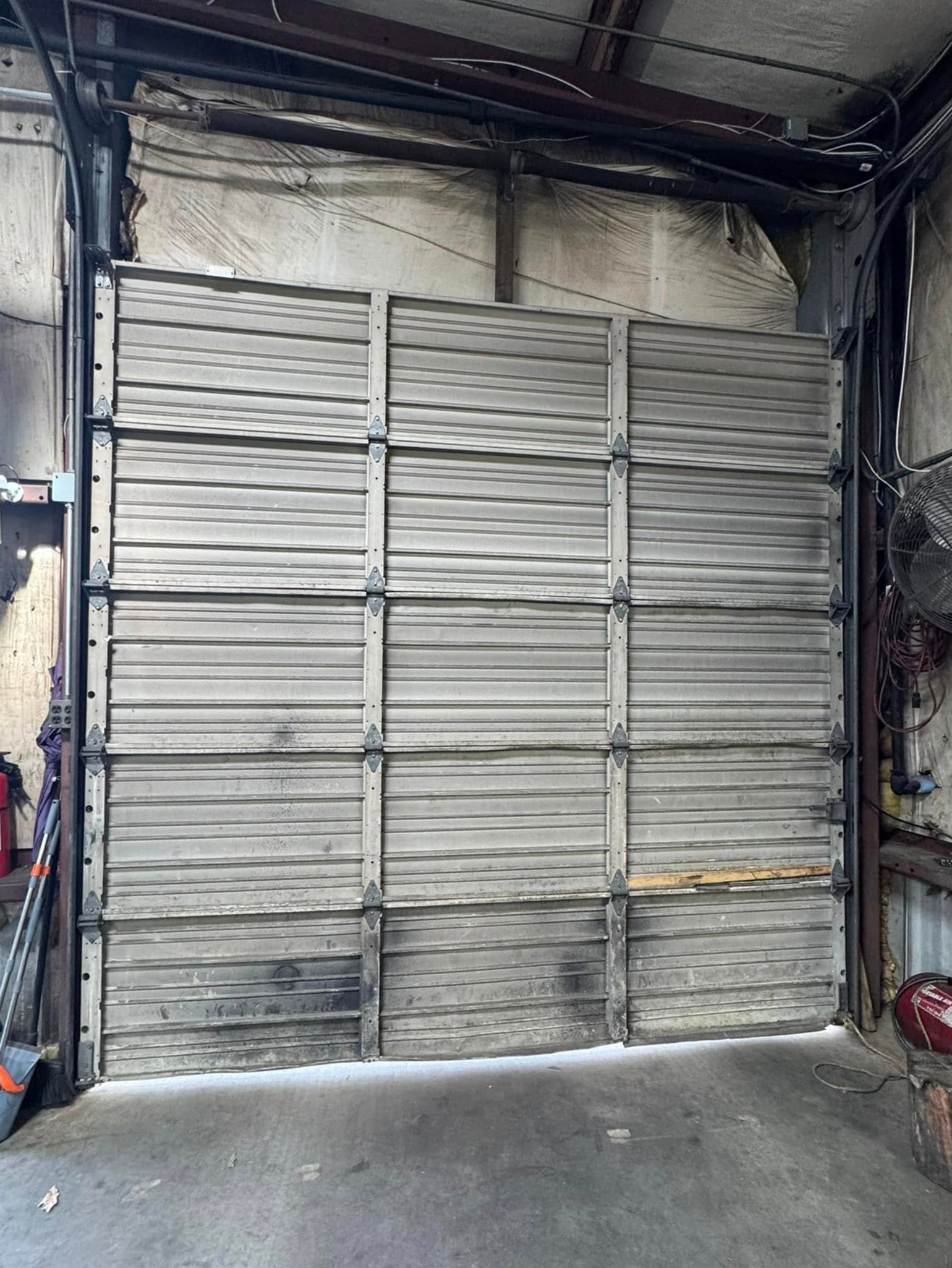 A large garage door is open in a garage.