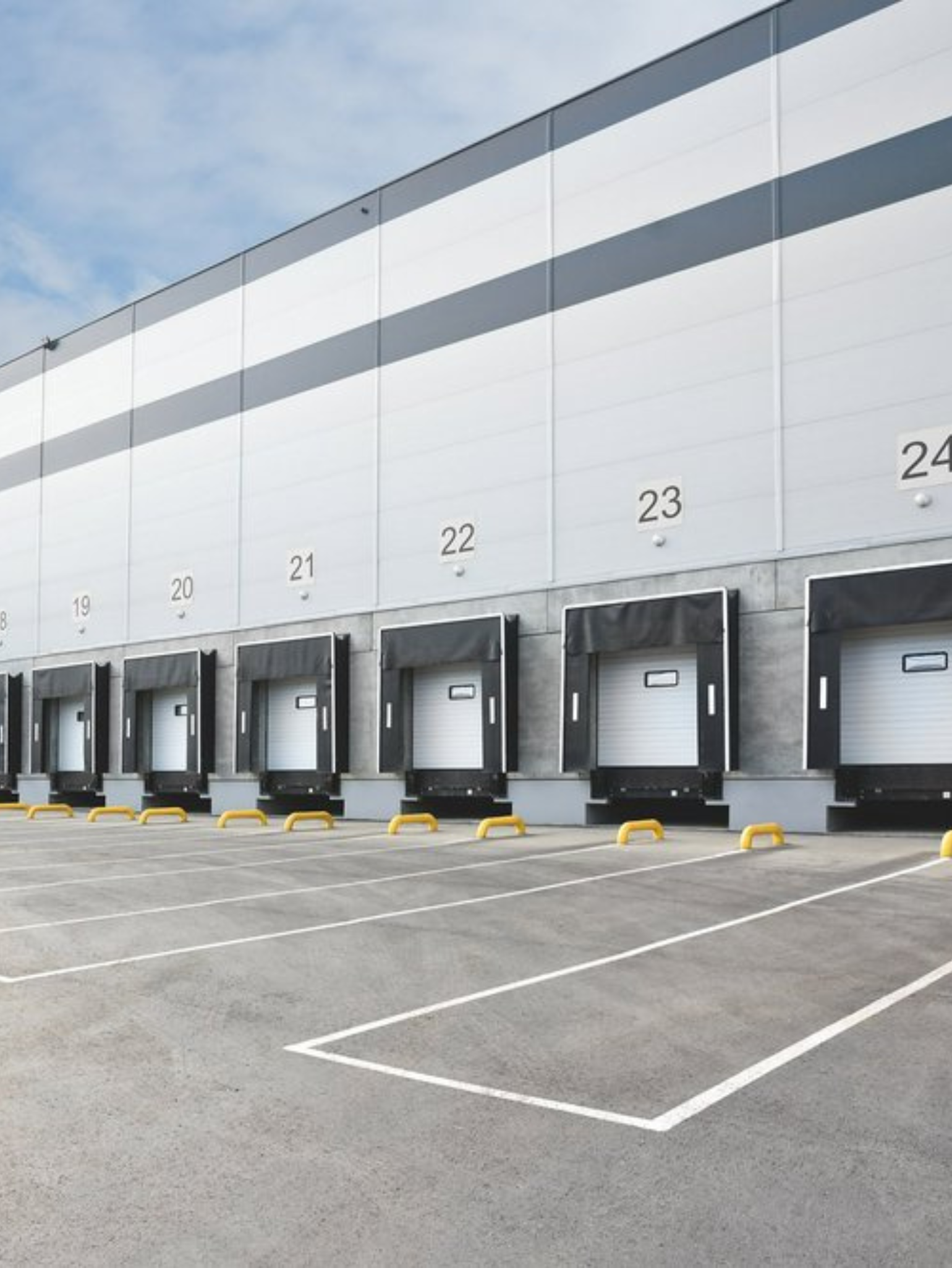 Loading docks on a warehouse with numbered bays and gray asphalt parking.