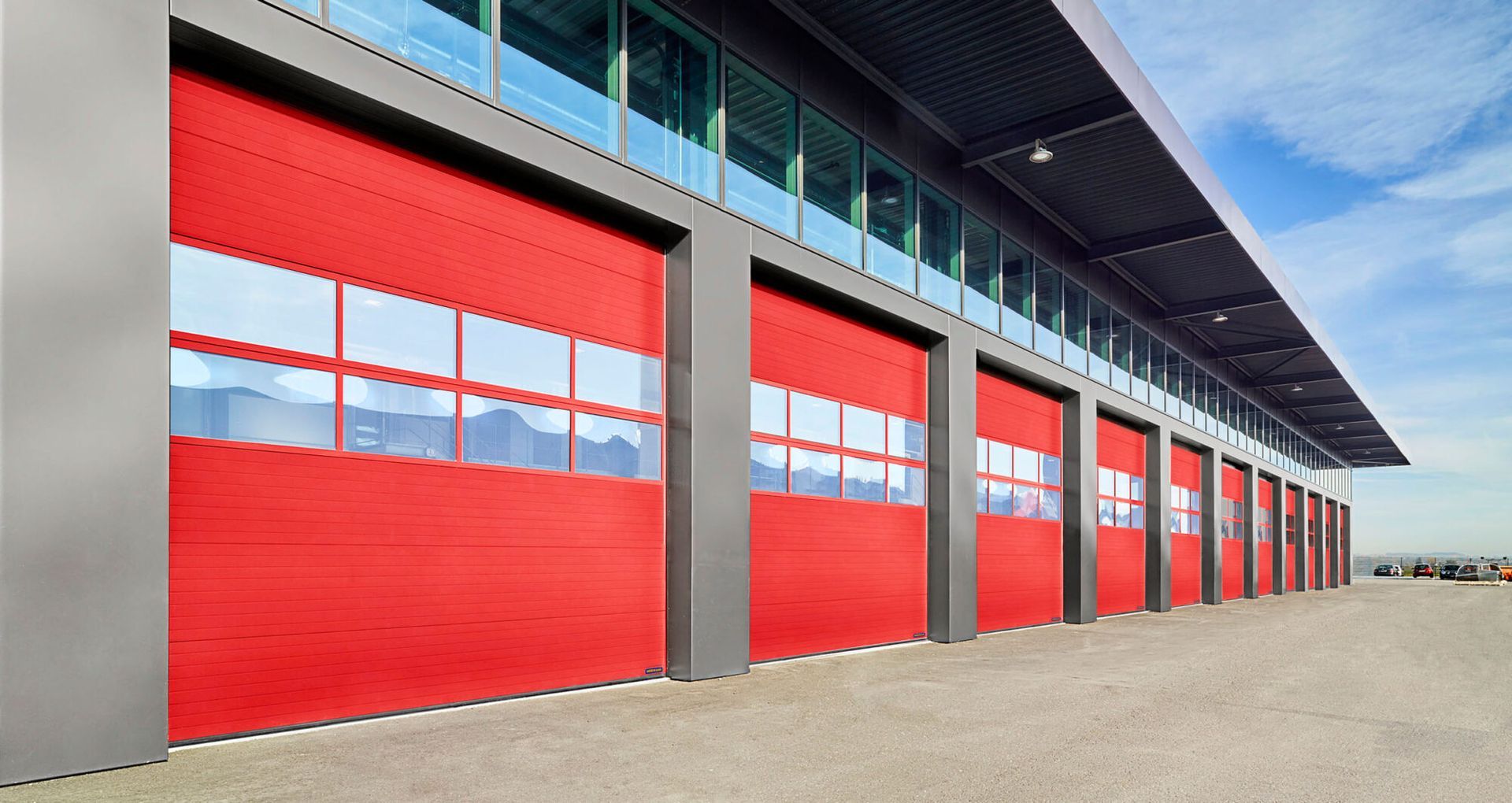 Red industrial doors with windows along a building facade.