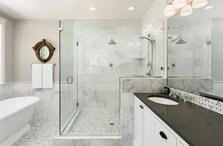Elegant white marble bathroom with glass shower, soaking tub, and long vanity.