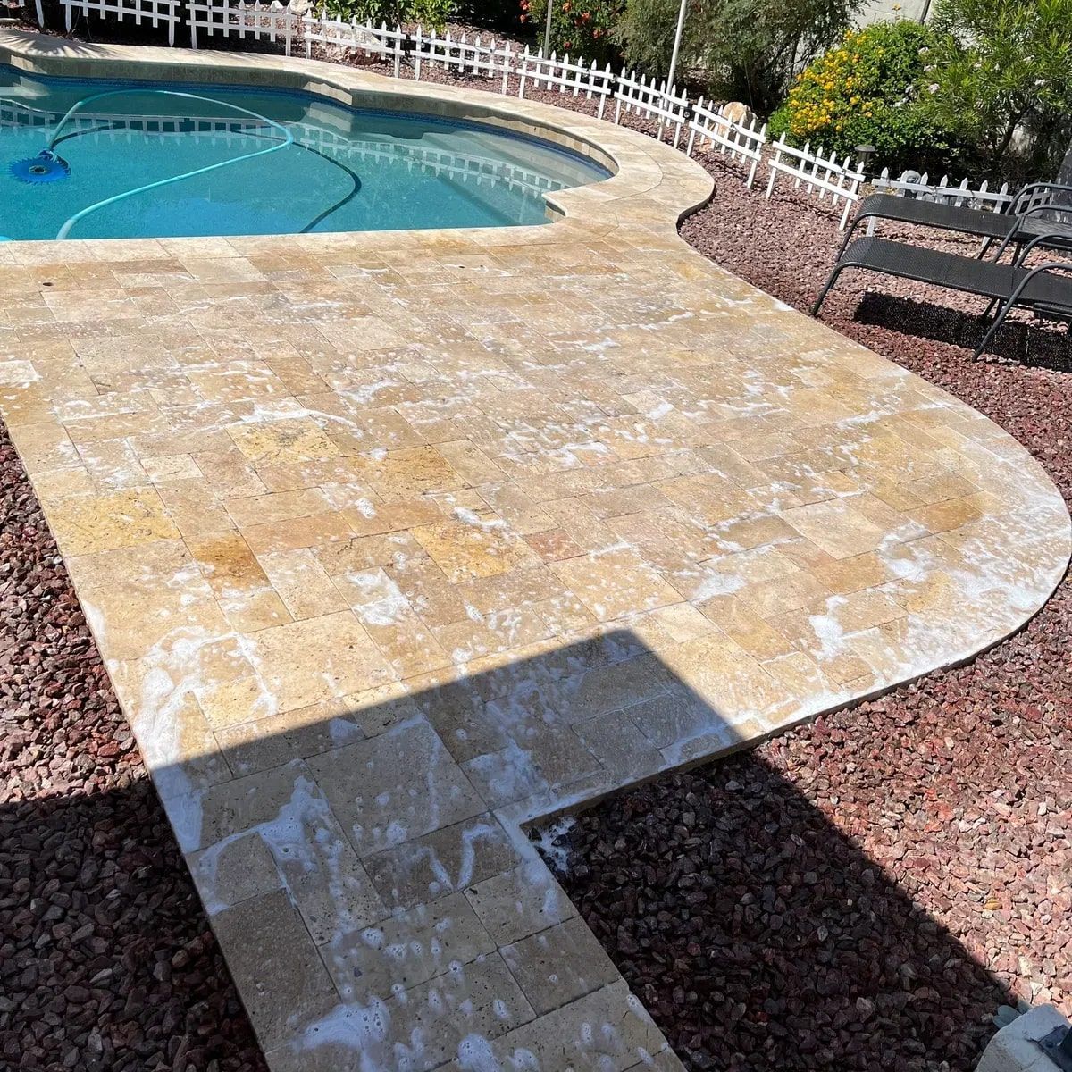 A swimming pool with a tiled deck and a fence around it.