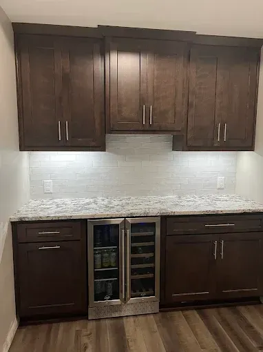 A kitchen with wooden cabinets , granite counter tops , and a wine cooler.
