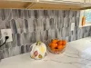 A kitchen counter with a bowl of oranges and a pumpkin on it.