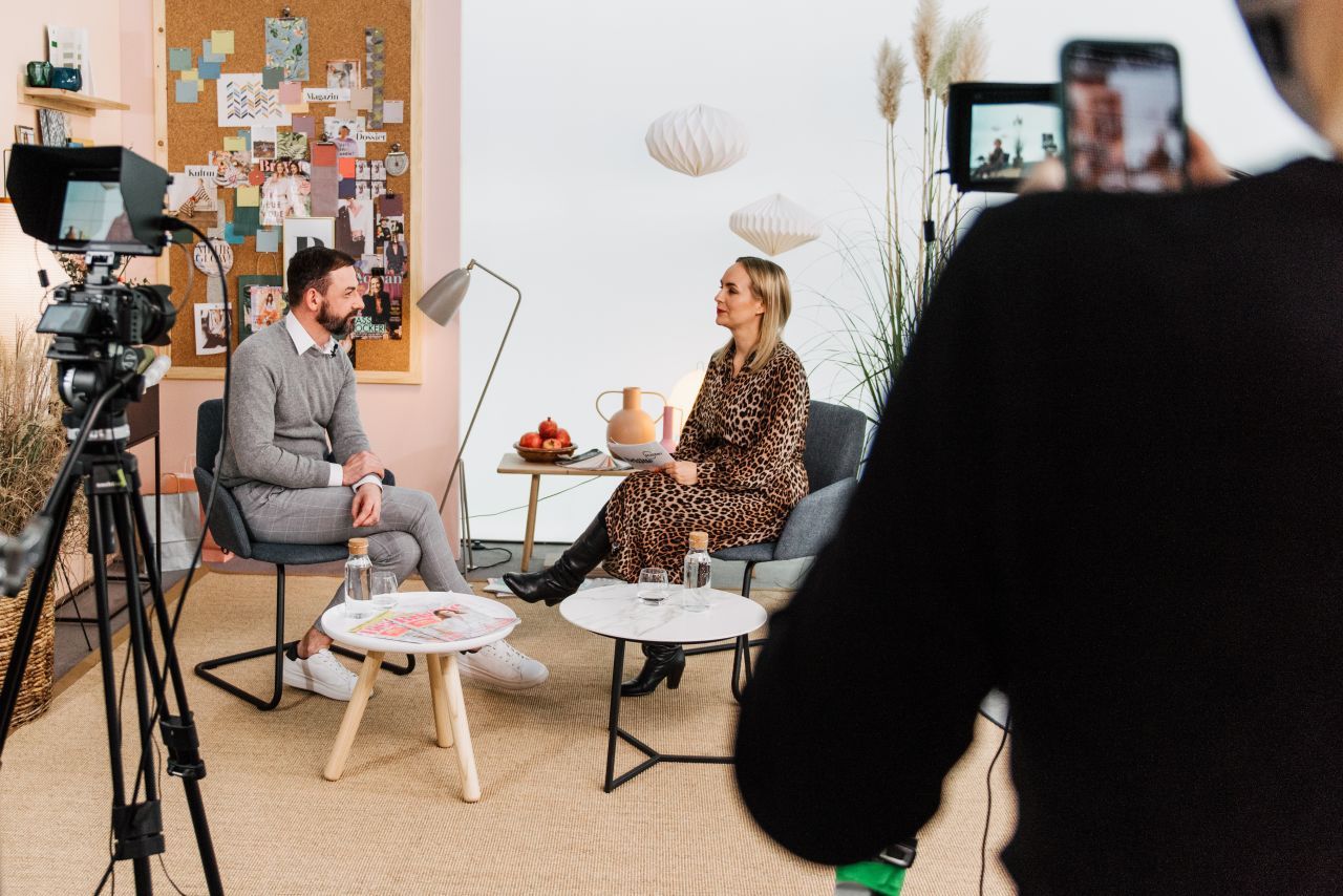 Ein Mann und eine Frau sitzen vor einer Kamera.