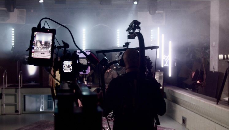 Ein Mann steht in einem dunklen Raum vor einer Kamera.