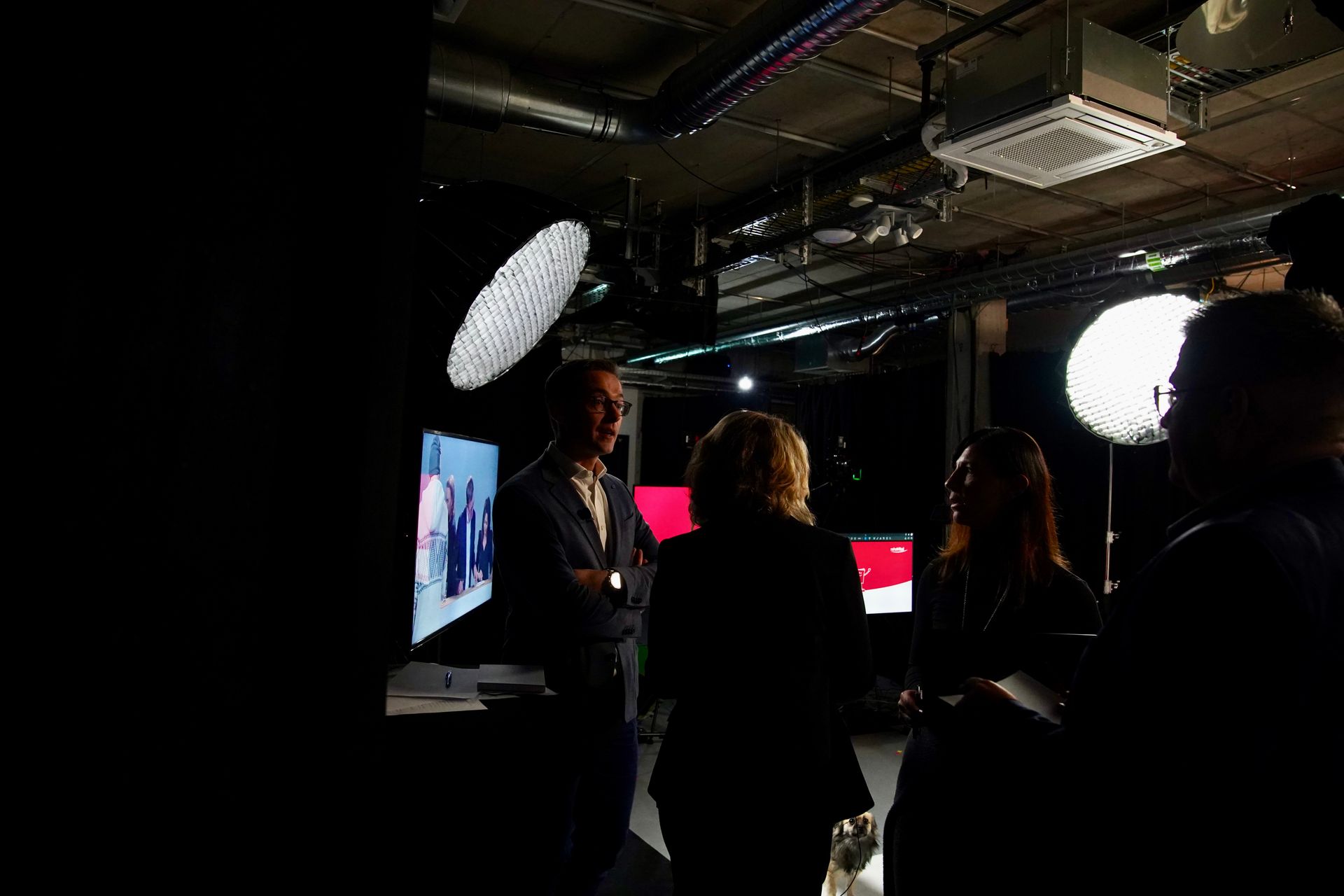 Eine Gruppe von Leuten steht in einem dunklen Raum und unterhält sich.