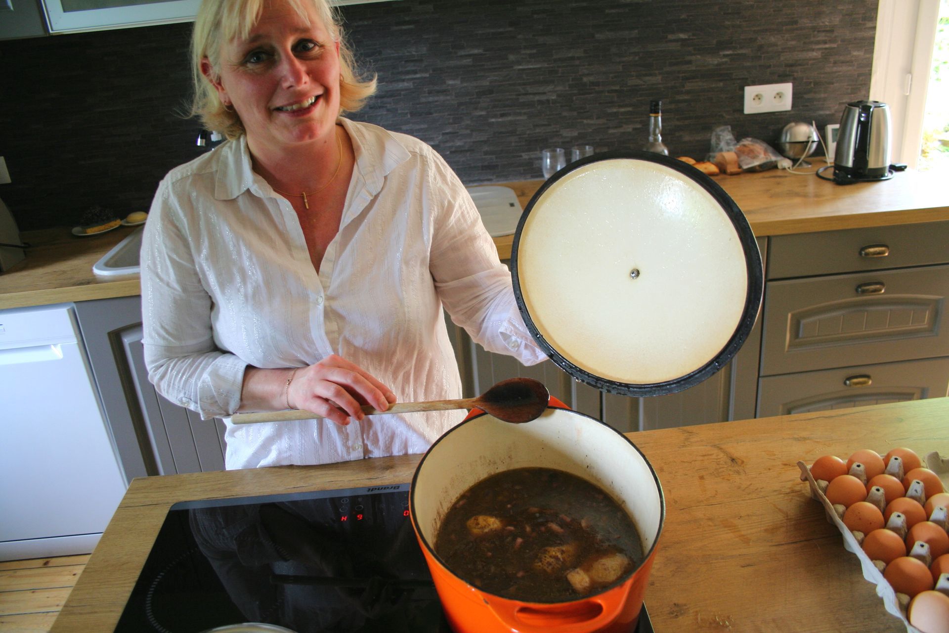 A woman is holding a bunch of carrots and radishes
