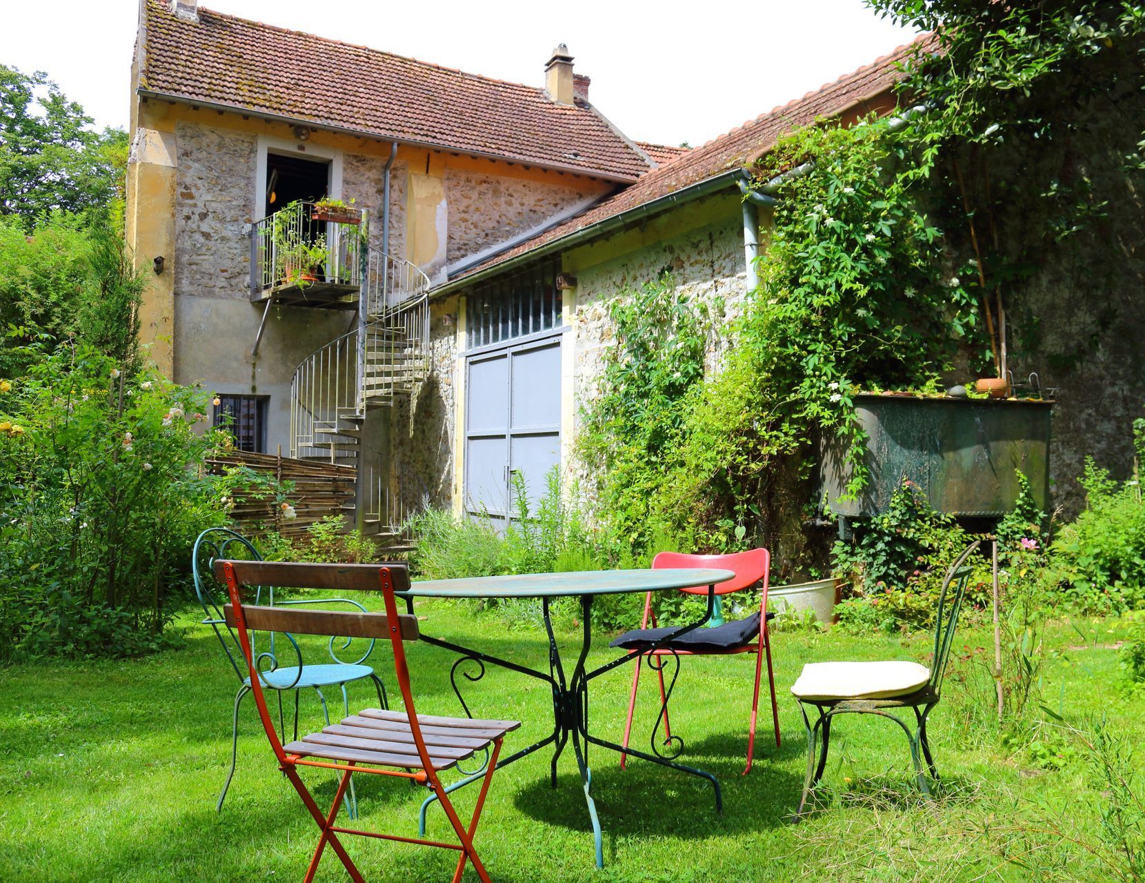 A little girl is kneeling down in a chicken coop holding a basket.