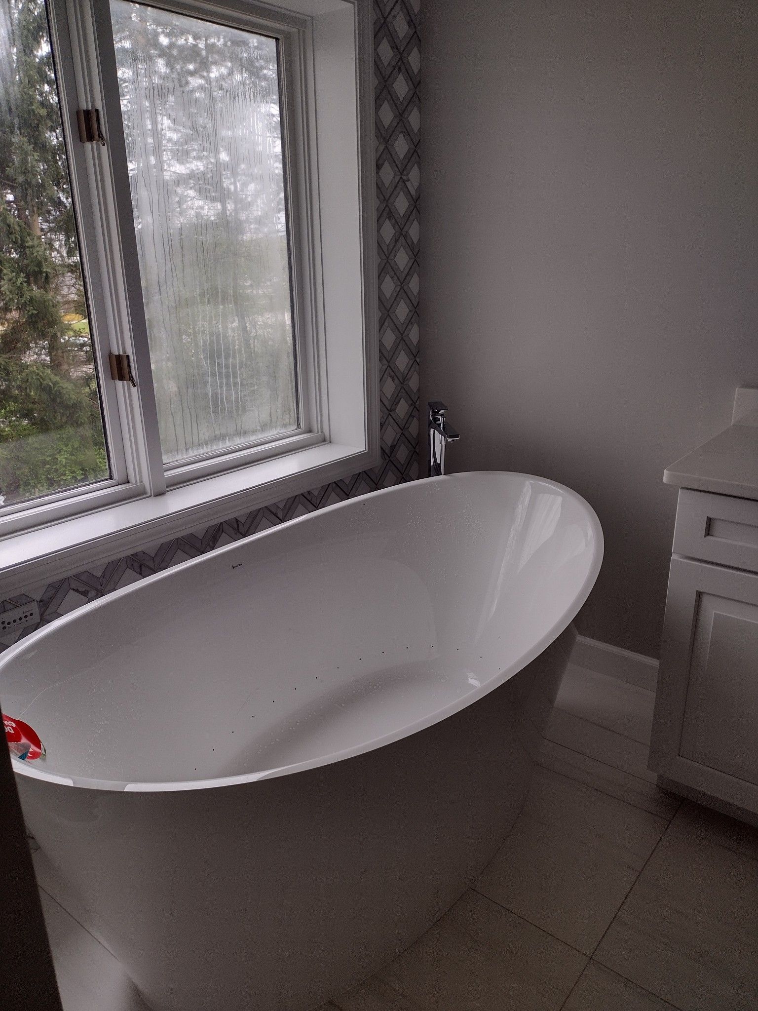 There is a bathtub in the bathroom next to a window.