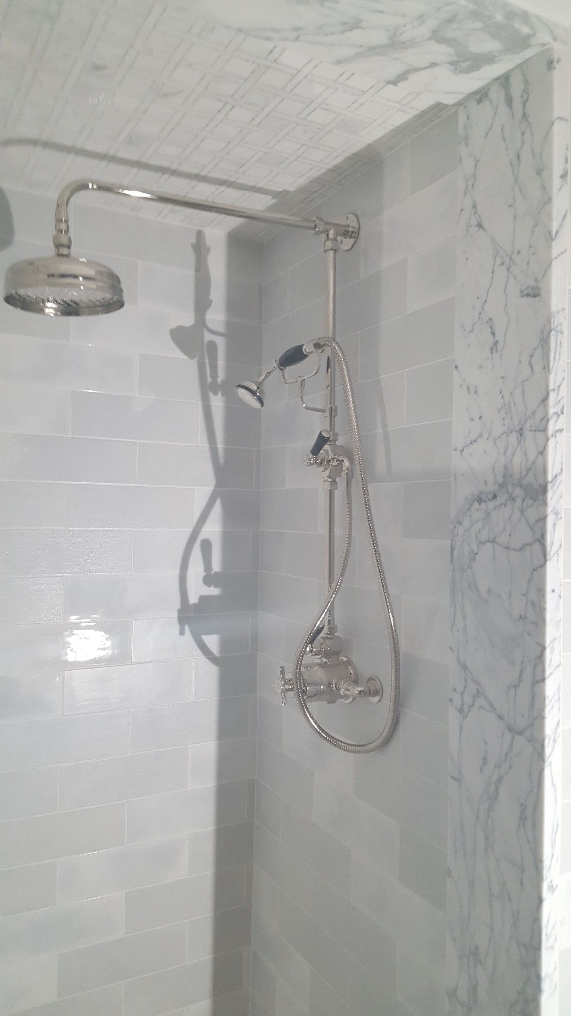 A shower head is hanging from the ceiling in a bathroom.