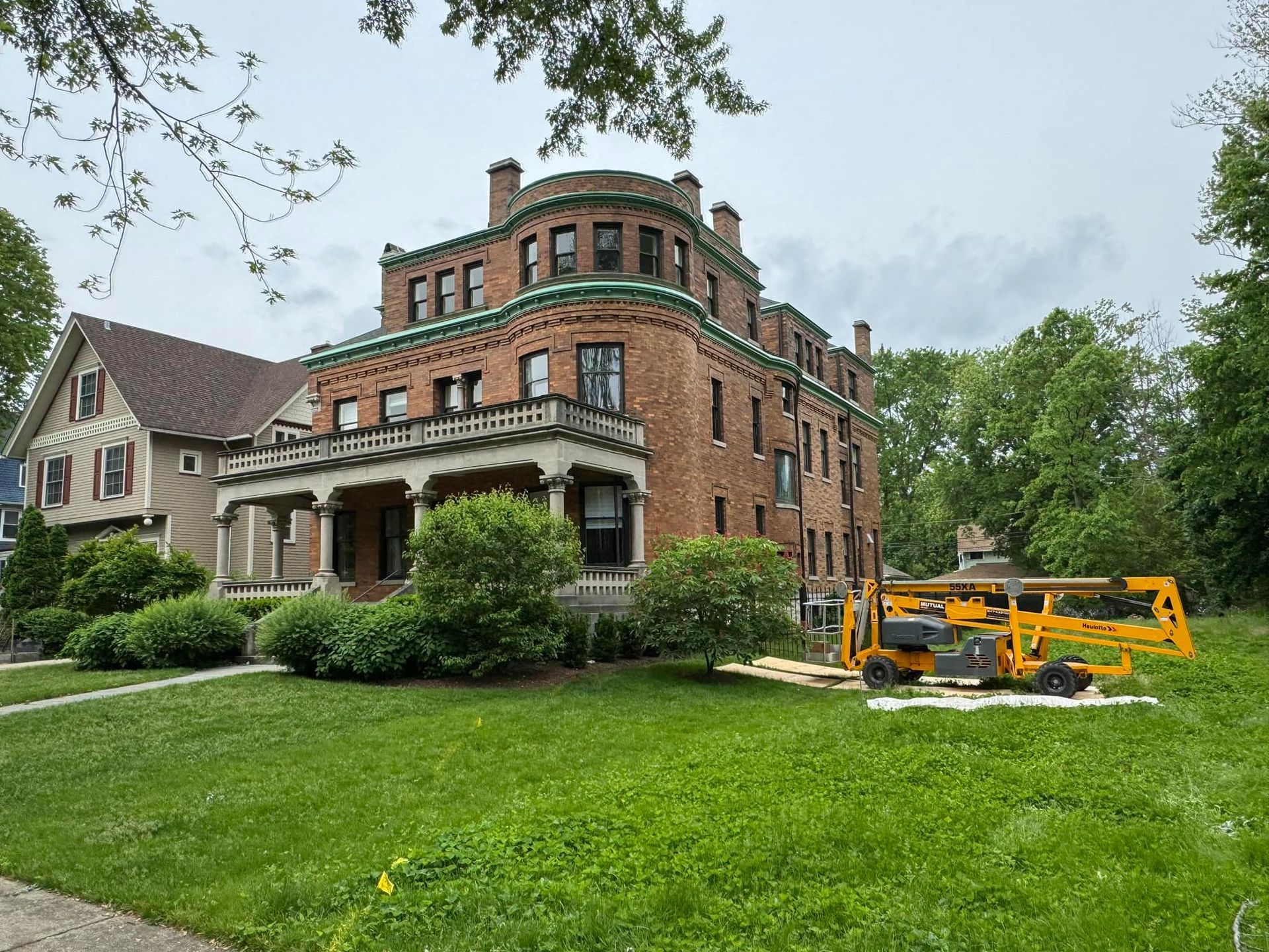 A large brick house with a yellow lift in front of it.
