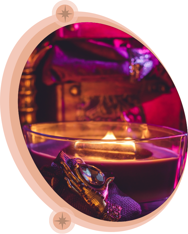 Lit candle in a glass bowl with jewel embellishment, purple and gold tones.
