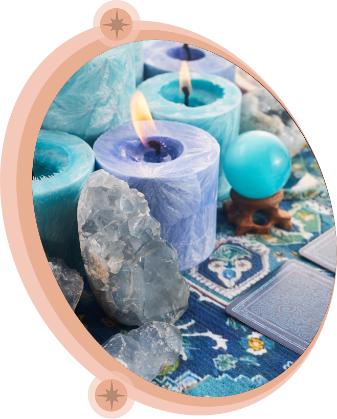 Blue candles, crystals, a crystal ball, and tarot cards on a blue patterned cloth.