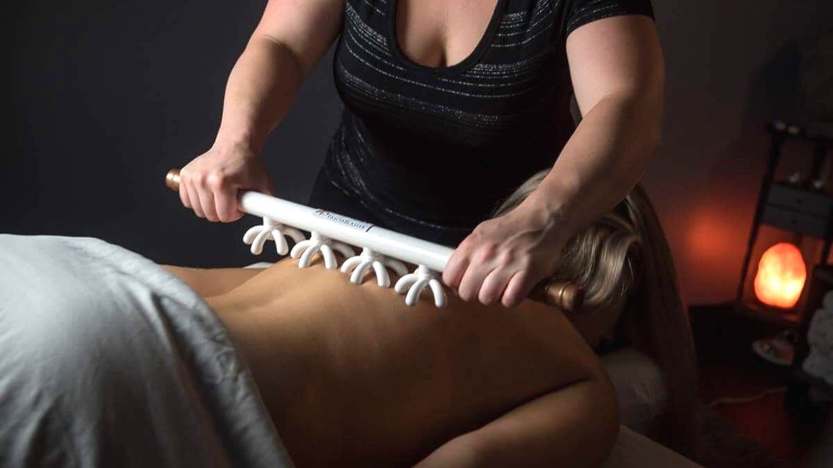 Sarah is giving a massage to a woman with a fascia blaster tool