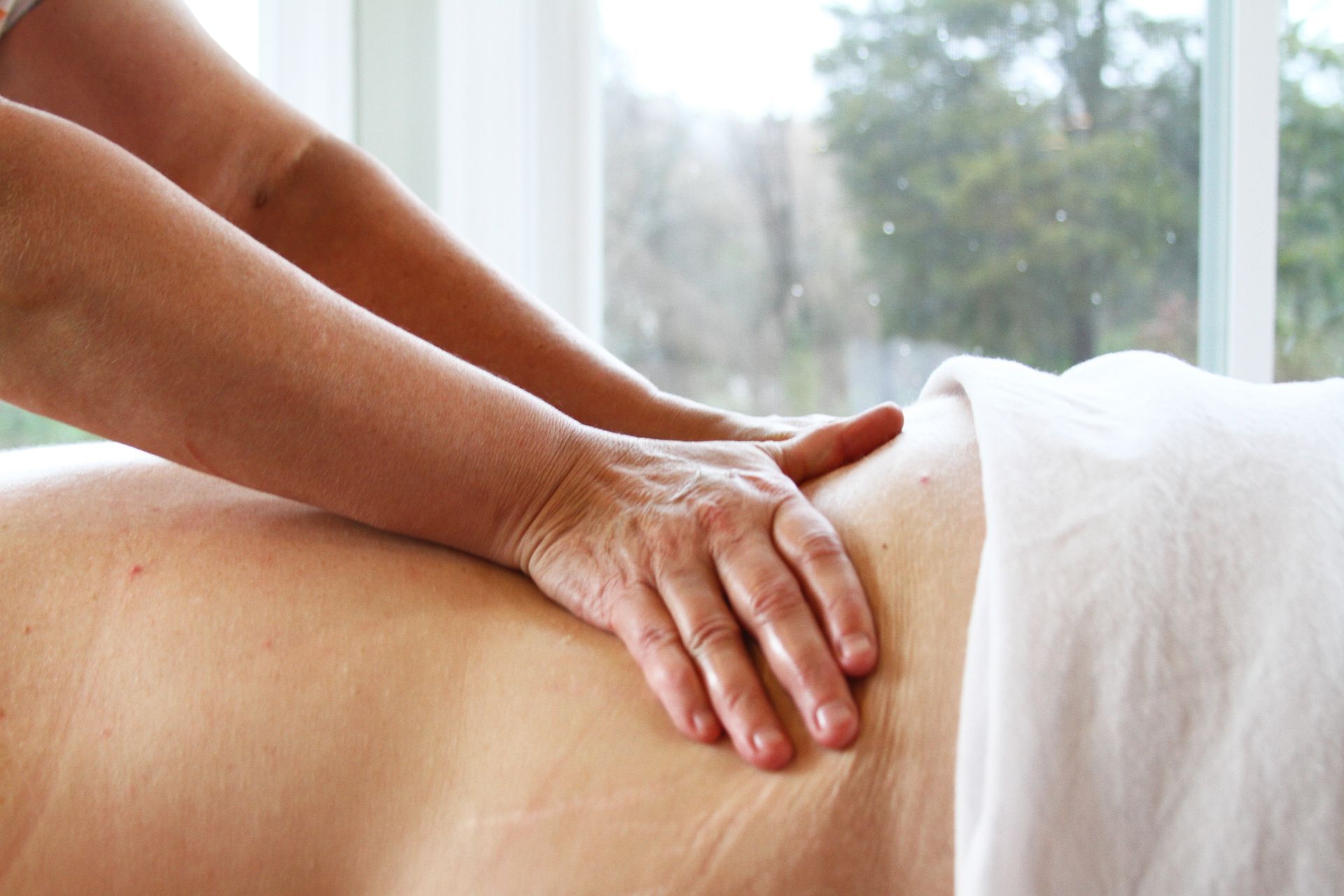 a woman is getting a deep tissue massage on her back in front of a window .