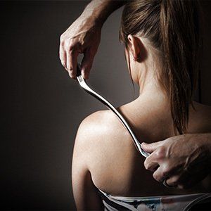 A woman is getting a massage with a metal tool on her back.