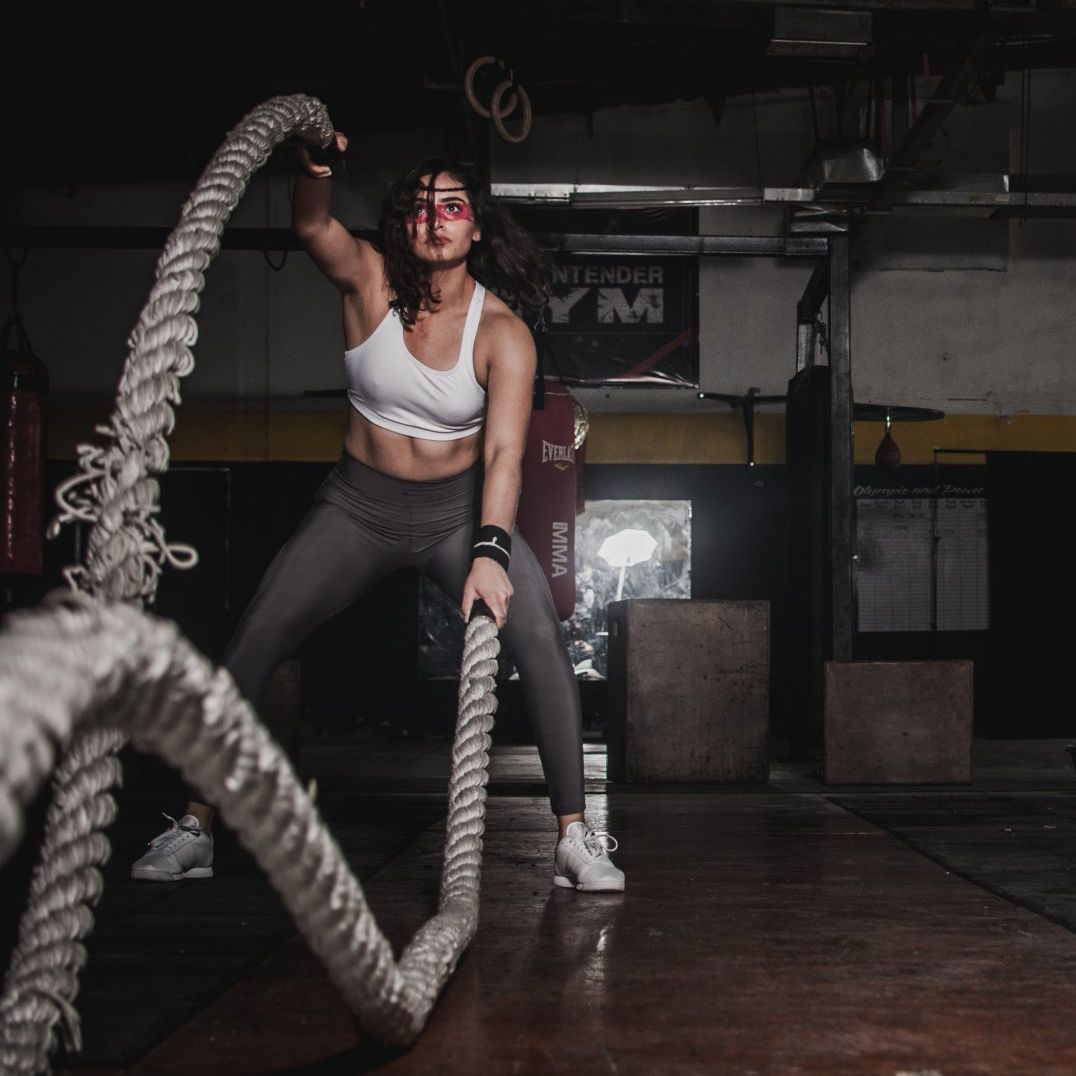 a woman is doing rope exercises at a CrossFit gym