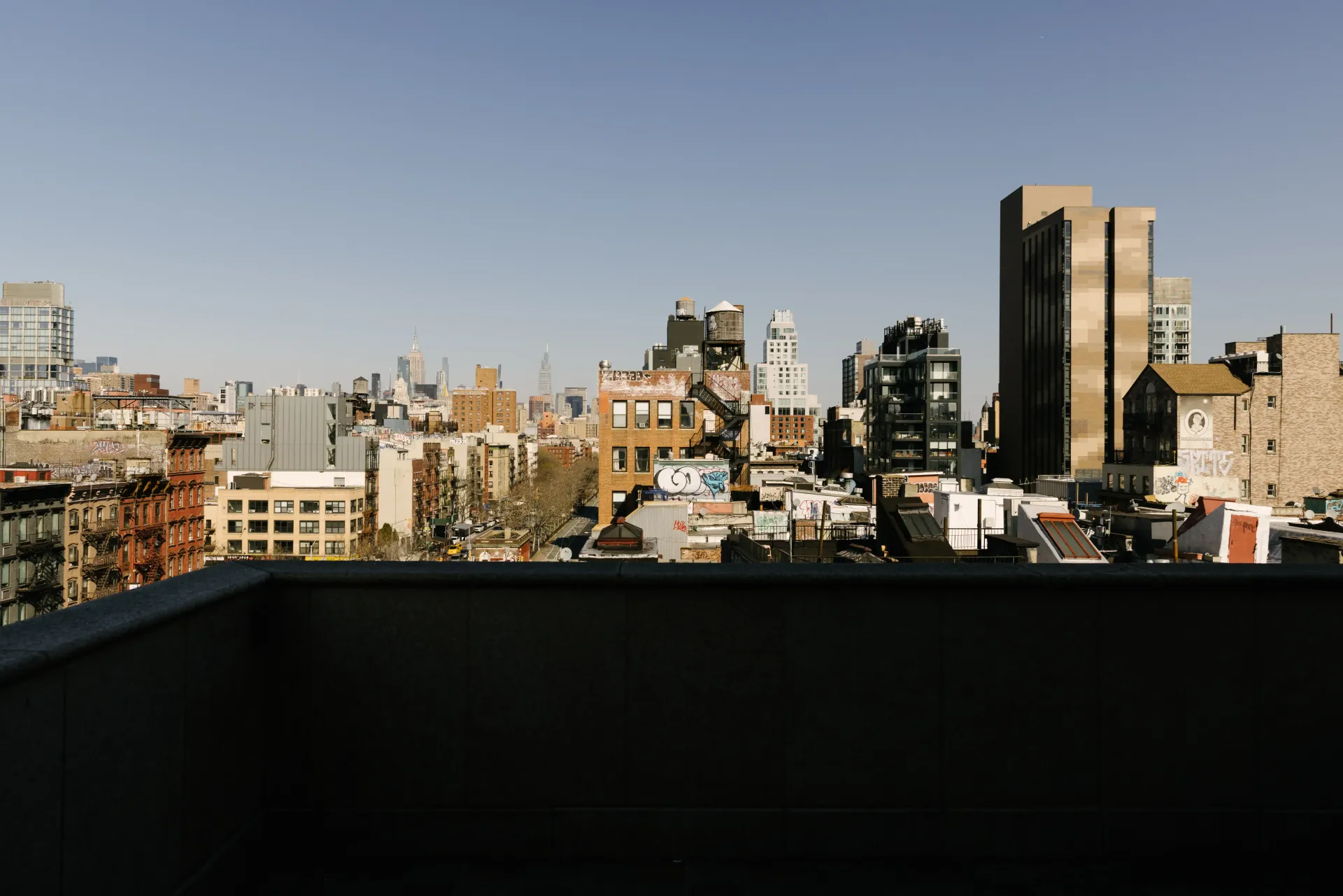 City skyline view from a rooftop on a sunny day. Brown buildings, blue sky.