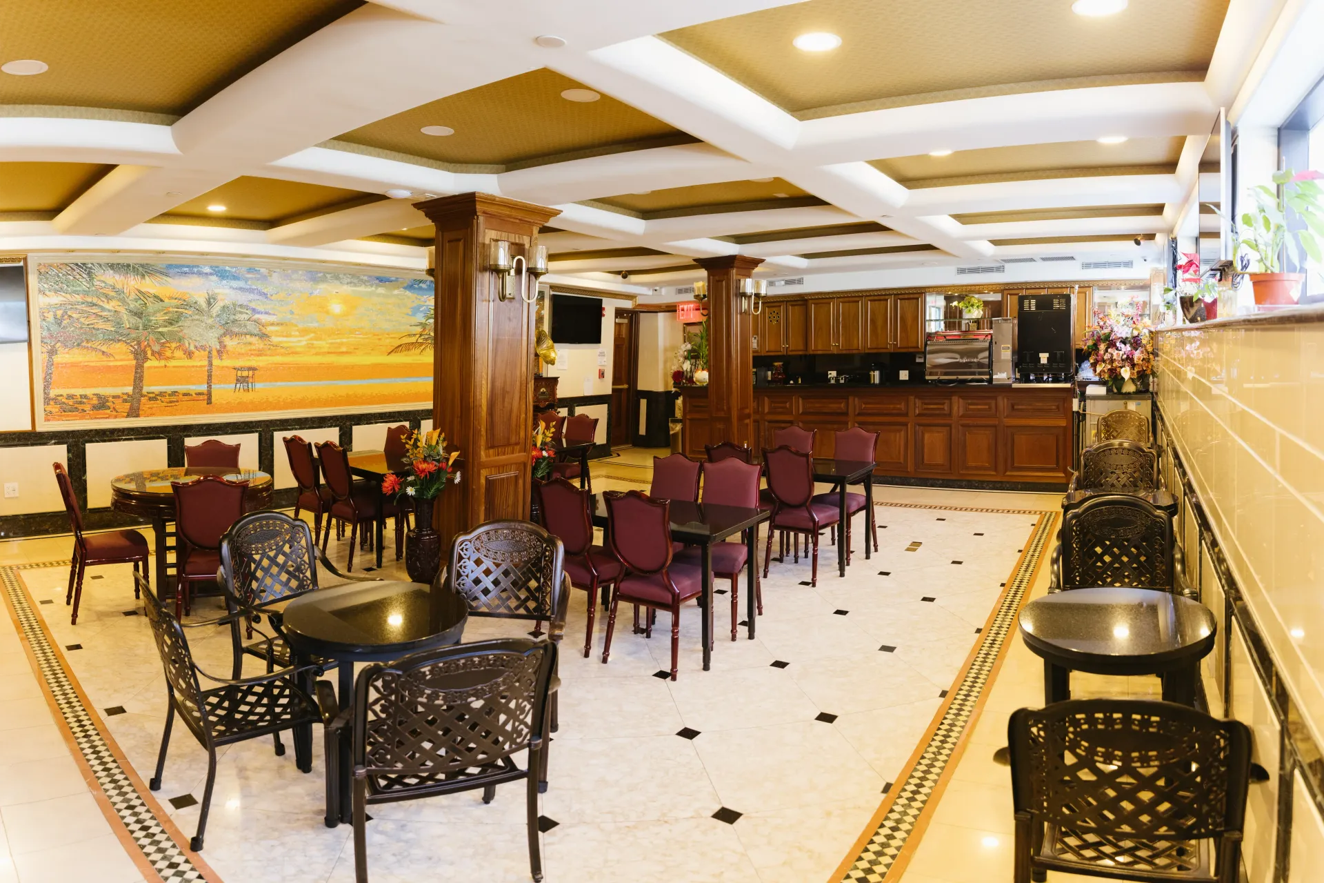 Restaurant interior with tables and chairs, a mural, and a counter.