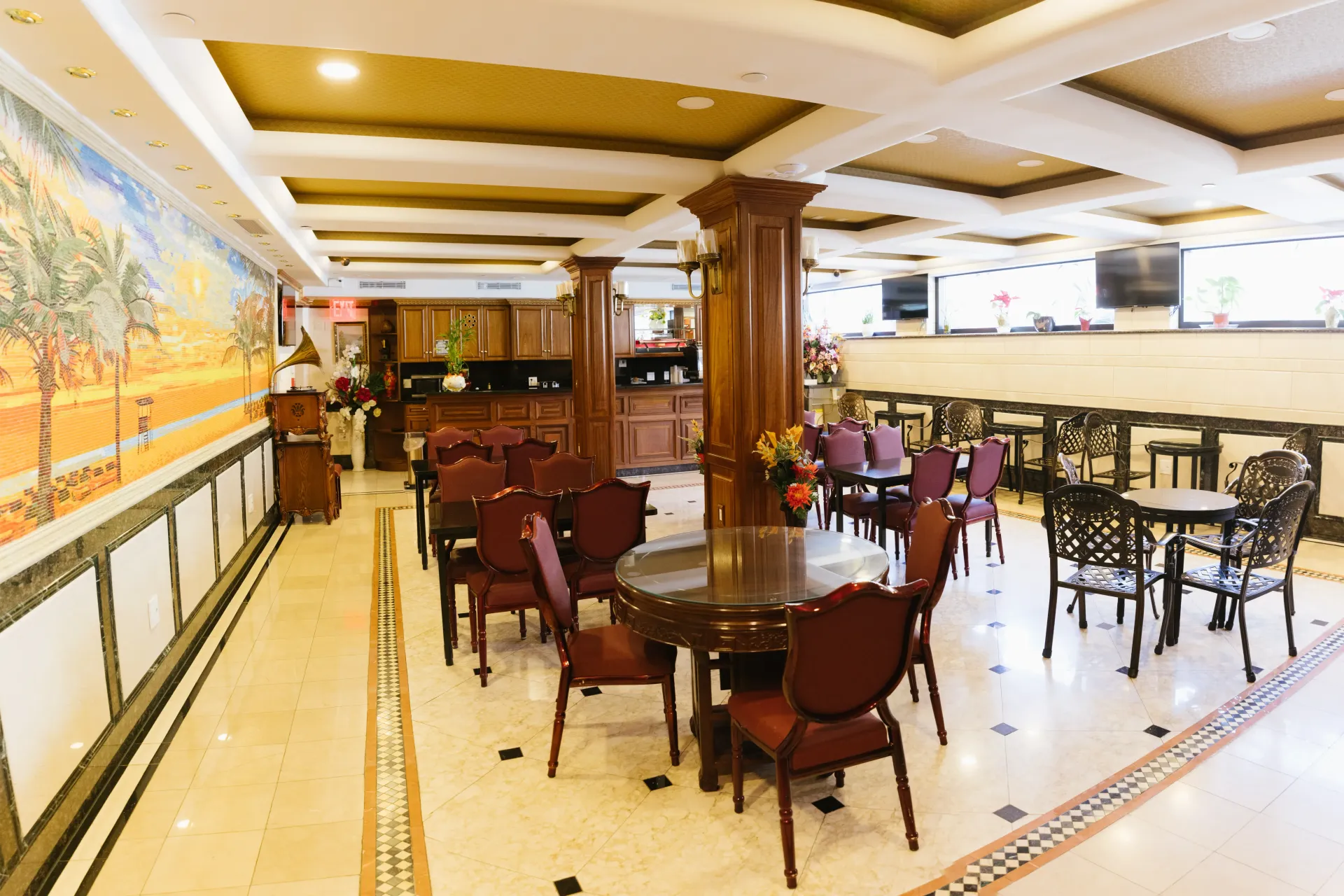 Restaurant interior with tables, chairs, and a mosaic wall art depicting a desert scene.